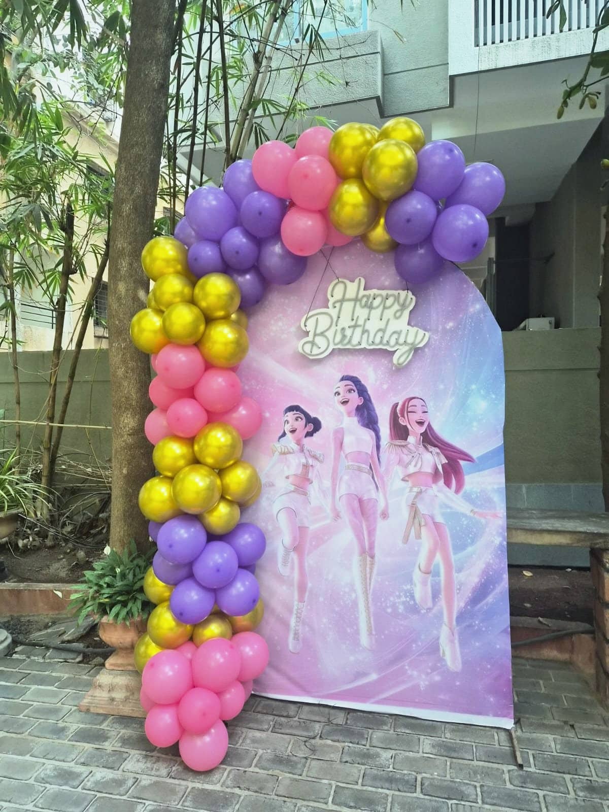 A balloon arch entrance flanked by life-size K-pop character cut-outs