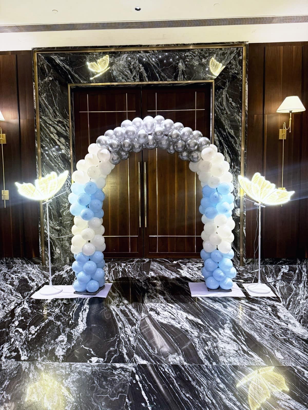 A silver, white and blue balloon arch framing a ballroom entrance